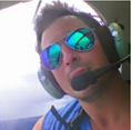 headshot of man with pilot headphones in a plane with blurred background