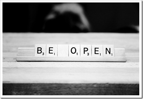 Image depicts a scrabble letter holder with the letters spelling "Be Open"