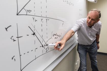 Professor drawing an economics graph on a whiteboard