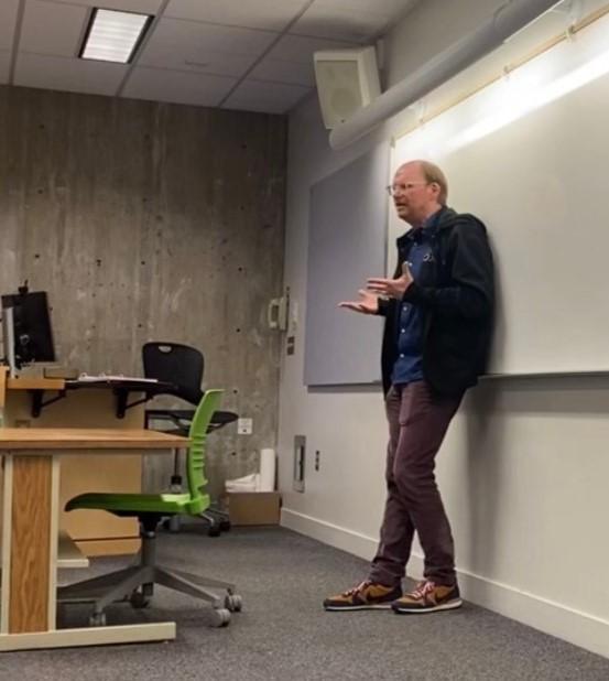 Professor Mark Staton speaking in front of a whiteboard.