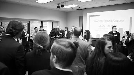 Students prepare to present their marketing cases while judges look on 