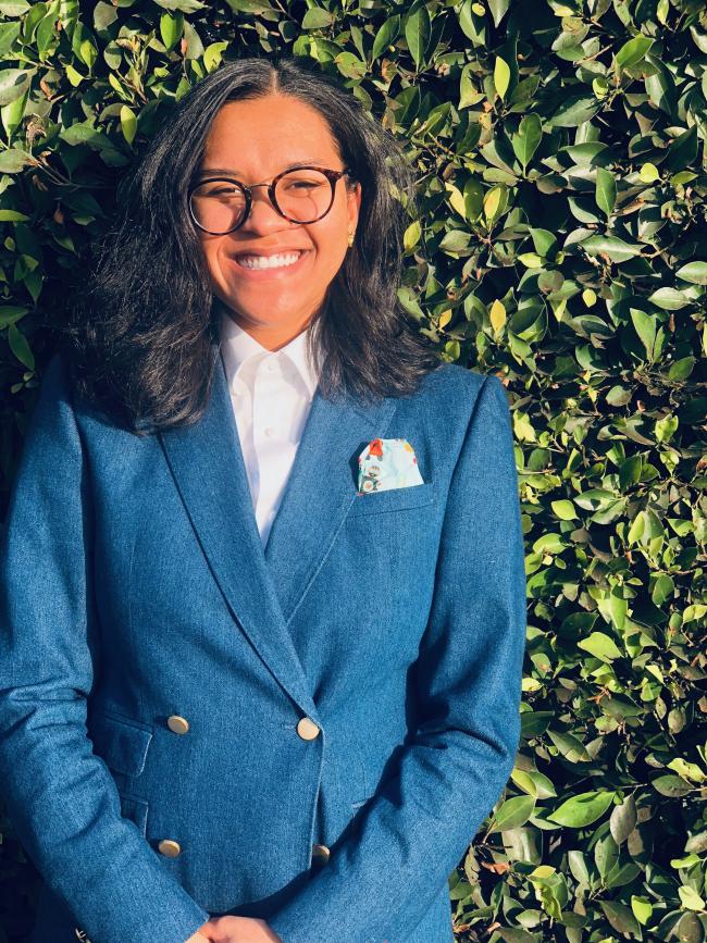Marciana Hill in a blue blazer next to a hedge